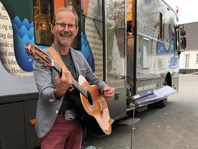 Peter Elmelund med en guitar foran Bogbussen